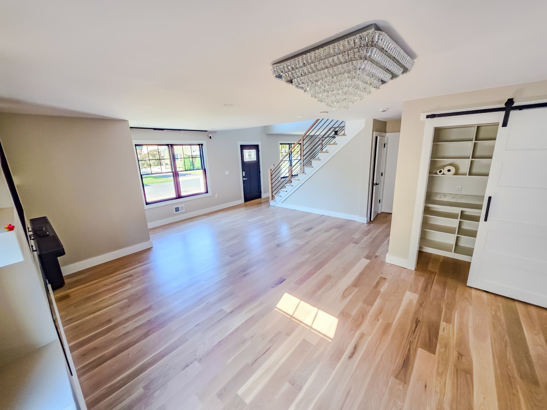 Open entry and living area with white oak floors, open stair and barn-door pantry