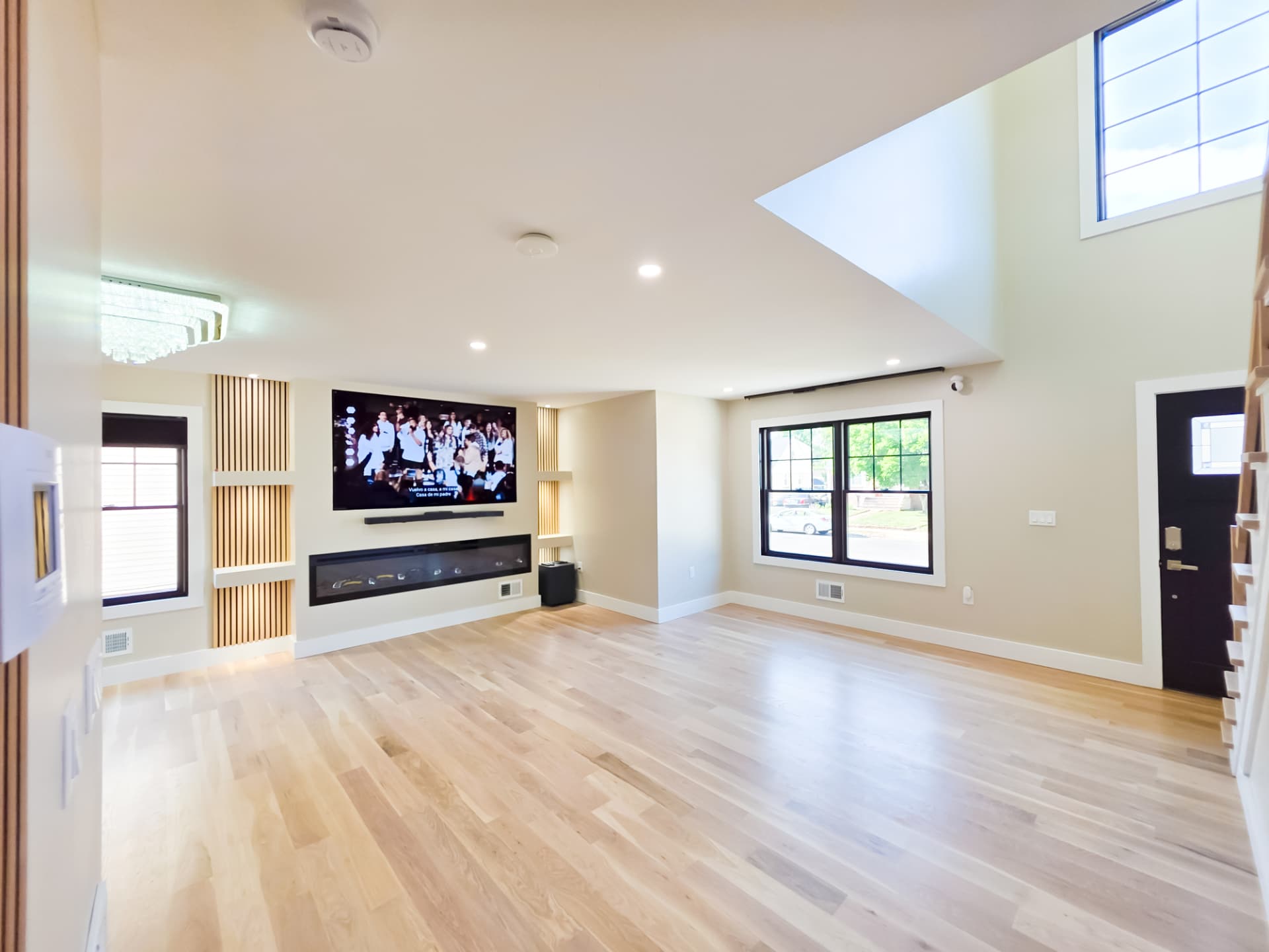 Living room with linear fireplace, mounted television and double-height ceiling opening