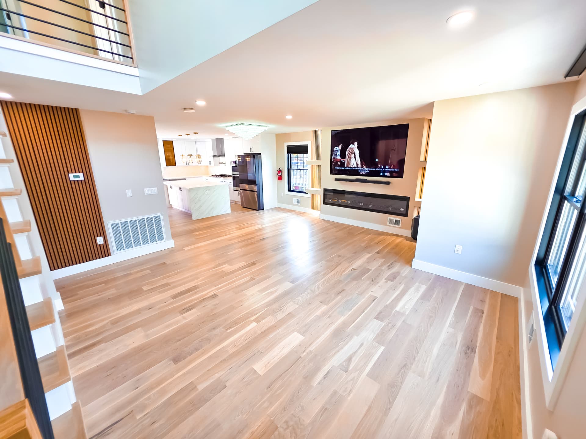 Living area with linear fireplace, slatted wood accent wall and view into the kitchen
